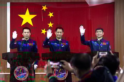 Astronauts (L-R) Tang Hongbo, Nie Haisheng, and Liu Boming wave at a press conference at the Jiuquan Satellite Launch Center ahead of the Shenzhou-12 launch. (Photo | AP)