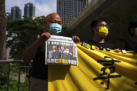 Pro-democracy activists holding a copy of Apple Daily newspaper and banner protest outside a court in Hong Kong, Saturday, June 19, 2021, to demand to release political prisoners. (Photo | AP)