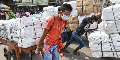 A worker pulls a cart at Sadar market that reopened after further ease in COVID-induced lockdown restrictions, in New Delhi. (Photo | PTI)