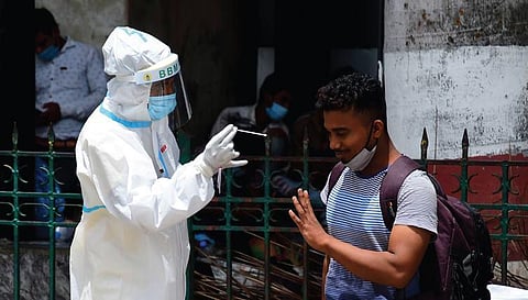 A health worker collects swab samples of a passenger at Krantivira Sangolli Rayanna  Railway Station in Bengaluru. (Photo | Shriram BN, EPS)