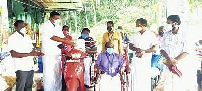 Kothamangalam MLA Antony John handing over a food kit to a beneficiary. All Kerala Wheelchair Rights Federation general secretary Rajeev Palluruthy is also seen