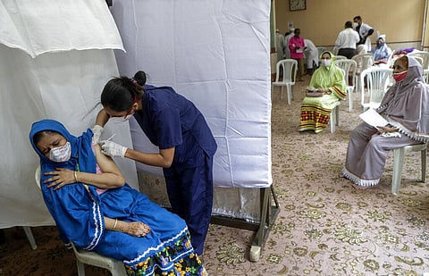 A woman gets inoculated against COVID-19 as others wait their turn at a vaccination center in Mumbai. (Photo | AP)