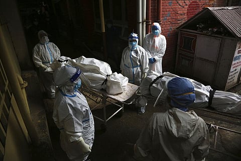 Paramedics get ready to load dead bodies of COVID-19 victims onto an ambulance for cremation at a government run hospital in Kathmandu. (Photo | AP)