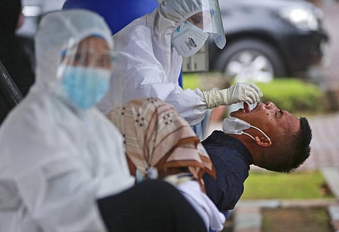A man reacts as a medical worker collects his nasal swab samples during a mass test for coronavirus at North Sumatra University (USU) Hospital in Medan, North Sumatra, Indonesia. (Photo | AP)