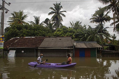 Sri Lankans ride a raft in an inundated street following heavy rainfall at Malwana, on the out skirts of Colombo. (Photo | AP)