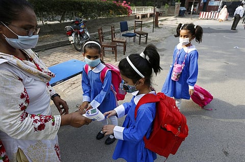 A teacher checks the body temperature of students as they arrive at school in Lahore, Pakistan, Monday, June 7, 2021. (Photo | AP)