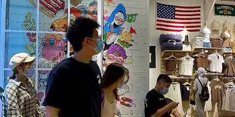 People wearing face masks visit a fashion boutique displaying an American flag in Beijing, Sunday, July 11, 2021. (Photo | AP)