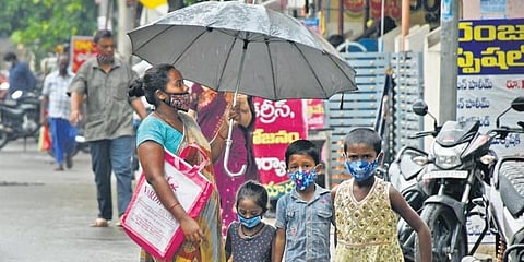 A mother protects her children from drizzle in Vijayawada on  Saturday. (Photo | Express)