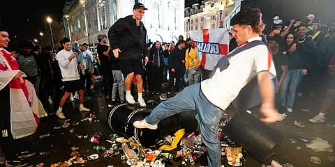 English fans kick and stand on a litter bin in Piccadilly Circus, London, after Italy beat England on penalties to win the UEFA Euro 2020 Final. (Photo | AP)