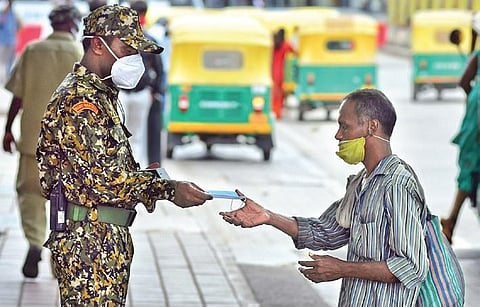 A BBMP marshal gives away a mask to a man in Bengaluru (Photo | Shriram BN)