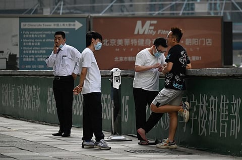 Workers chat outside an office building in Beijing, China, on July 15, 2021. (Photo | AFP)