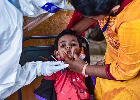 A health worker collects swab sample of a child for Covid-19 test. (Photo | PTI)