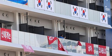 Banners with the words 'I still have the support of 50 million Korean people', are removed from balconies at the Olympic athletes' village in Tokyo. (Photo | AP)