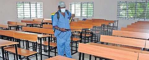 A staffer sanitises a classroom at a school in Tumakuru, prepping it for SSLC exams.| Express
