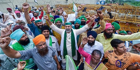 BKU spokesperson Rakesh Tikait and farmers raise slogans during their protest against three farm reform laws, at Ghazipur border. (Photo | PTI)