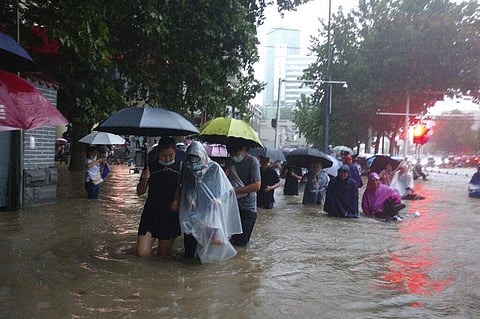 People move through flood water after a heavy downpour in Zhengzhou city, central China's Henan province. (Photo | AP)