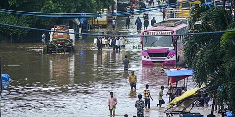 Commuters wade through a flooded road after heavy rain at Bhiwandi in Thane. (Photo | PTI)