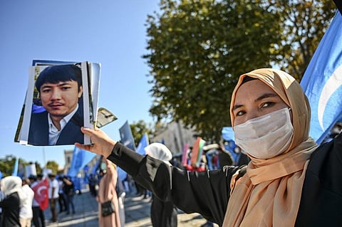 A supporter of China's Muslim Uighur minority shows a picture of her relative jailed in China. (File Photo| AFP)