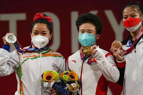 Gold medalist, Hou Zhihui of China, center, stands with silver medalist Mirabai Chanu Saikhom of India, left, and bronze medalist Windy Cantica Aisah of Indonesia, right. (Photo | AP)
