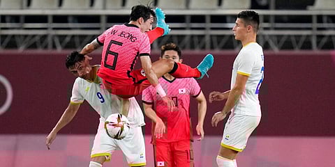 George Ganea of Romania, left, and South Korea's Jeong Seungwon fight for the ball during a men's soccer match at the 2020 Summer Olympics in Kashima, Japan. (Photo | AP)