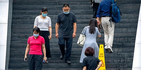 People wearing face masks to protect against COVID-19 walk down stairs at a shopping and office complex in Beijing. (Photo | AP)