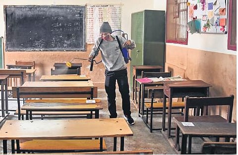 A worker seen spraying sanitizer before the opening of classes 10 and 12 at DTEA school, Pusa Road, in New Delhi onSunday | PARVEEN NEGI