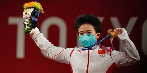 Hou Zhihui of China celebrates on the podium after winning the gold medal in the women's 49kg weightlifting event, at the 2020 Summer Olympics in Tokyo, Japan. (Photo | AP)