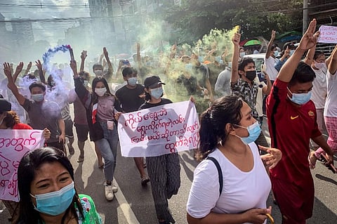 Protesters make the three-finger salute and hold flares during a demonstration against the military coup in Yangon on July 3, 2021. (Photo | AFP)