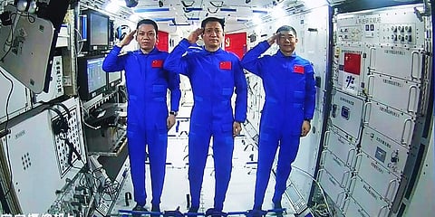 Chinese astronauts, from left; Tang Hongbo, Nie Haisheng, and Liu Boming salute from aboard China's space station core module Tianhe during a video conversation with Chinese President. (Photo | AP)