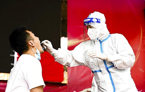 In this photo released by Xinhua News Agency, a medical worker collects a swab sample for nucleic acid test in Ruili City of southwest China's Yunnan Province. (Photo | AP)