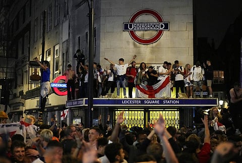 England fans react as they stand on the roof of Leicester Square underground station after England won the Euro 2020 soccer championship semifinal match. (Photo | AP)