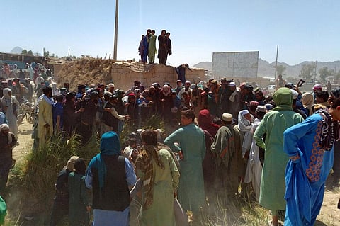 Taliban fighters and Afghans gather around the body of a member of the security forces who was killed, inside the city of Farah. (Photo | AP)