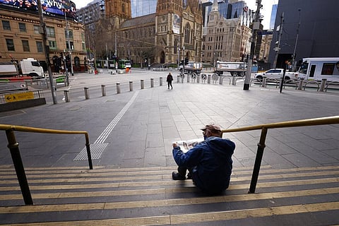 A man reads a newspaper on the steps of Flinders Street Station in Melbourne, Australia, Wednesday, Aug. 11, 2021. (Photo | AP)