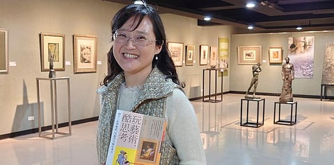 In this photo taken on March 23, 2021, Taiwanese author Iris Chiang holds her book 'Play with Art' at the saloon featuring Taiwanese artist YUYU Yang's work in Taipei, Taiwan. (Photo | AP)