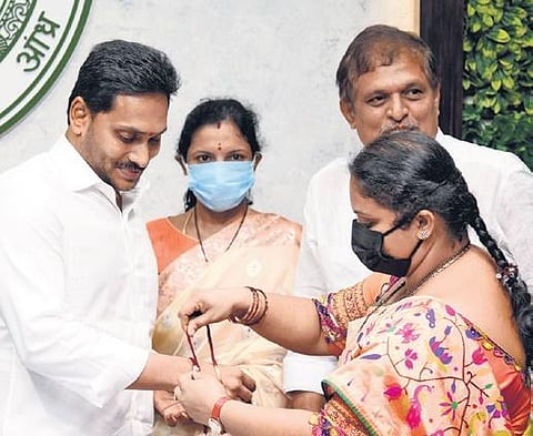 A woman beneficiary of YSR Nethanna Nestham ties Rakhi to CM Jagan Mohan Reddy at Tadepalli on Tuesday. (Photo | Express)