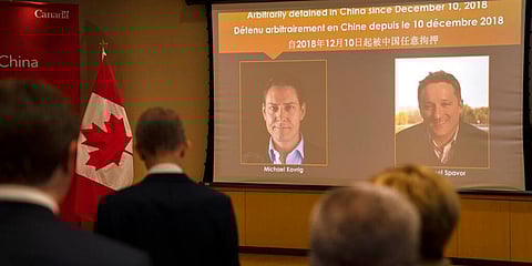A video screen displays images of Canadians Michael Kovrig, left, and Michael Spavor at the Canadian Embassy in Beijing, Aug 11, 2021. (Photo | AP)