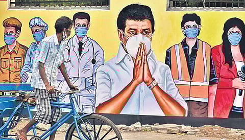 A man with his mask well down the chin rides near a wall painting of CM MK Stalin and frontline workers appealing the public to wear masks, at Kasimedu. (File photo| P Jawahar, EPS)