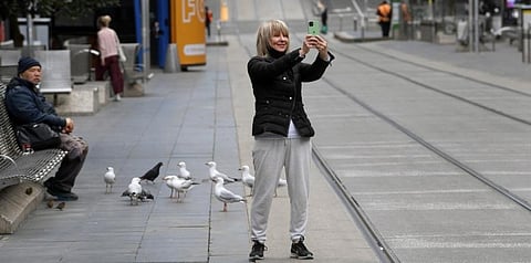 A woman takes a selfie in a near-deserted central business district in Melbourne on August 13, 2021 as the city endures its sixth lockdown. (Photo | AFP)