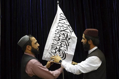 Taliban officials arrange a Taliban flag, before a press conference by Taliban spokesman Zabihullah Mujahid, at the Government Media Information Center, in Kabul. (Photo | AP)