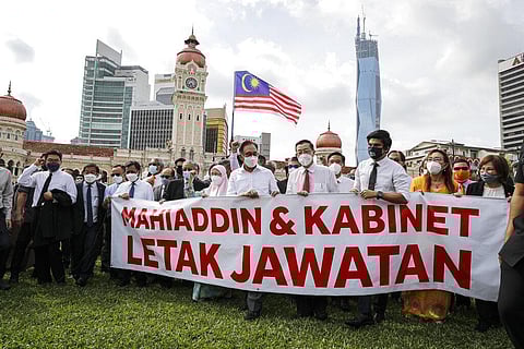 Malaysian opposition members Anwar Ibrahim, fourth from left, and Mahathir Mohamad, second from left in blue mask, hold a banner reading 'Muhyiddin and Cabinet resign' during a protest | AP