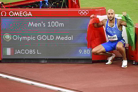 Lamont Marcell Jacobs, of Italy, poses next to the scoreboard after winning the final of the men's 100-meters at the 2020 Summer Olympics. (Photo | AP)