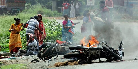 People injured in poll violence sit by the side of a road as a vehicle is set on fire by locals during Panchayat polls in Nadia district of West Bengal. (File photo | PTI)