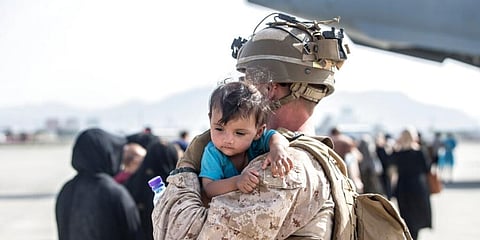 A US Marine calms an infant during an evacuation at Hamid Karzai International Airport in Kabul. (Photo | AP)