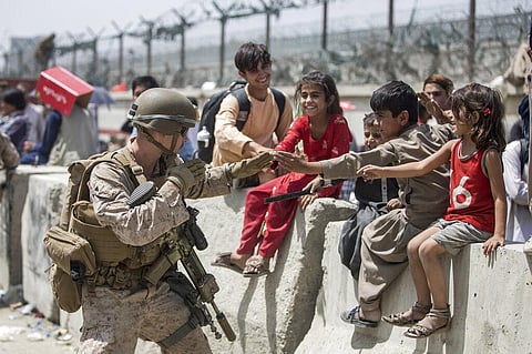 A Marine with Special Purpose Marine Air-Ground Task Force-Crisis Response-Central Command plays with children waiting to process during an evacuation at Kabul airport. (Photo | AP)