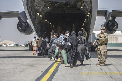 Families begin to board a U.S. Air Force Boeing C-17 Globemaster III during an evacuation at Hamid Karzai International Airport in Kabul. (Photo | AP)