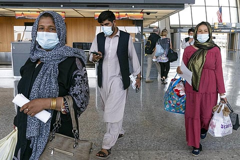 Families evacuated from Kabul, Afghanistan, walk through the terminal before boarding a bus after they arrived at Washington Dulles International Airport. (Photo | AP)