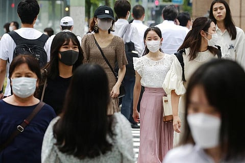 People wearing face masks to help protect against the spread of the coronavirus walk across an intersection (Photo | AP)