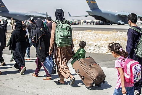 Families walk towards their flight during ongoing evacuations at Hamid Karzai International Airport, Kabul. (Photo | AP)