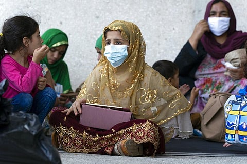 Families evacuated from Kabul, Afghanistan, wait outside the terminal to board a bus after they arrived at Washington Dulles International Airport. (Photo | AP)