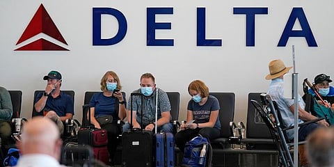 People sit under Delta sign at Salt Lake City International Airport on July 1, 2021, in Salt Lake City. (Photo | AP)